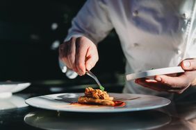 A chef adding finishing touches to a plate.